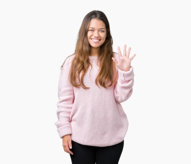 Gösterilen ve parmakları ile işaret izole arka plan üzerinde pembe kış kazak giyen genç güzel esmer kadın kendinden emin ve mutlu gülümseyerek süre beş numara.