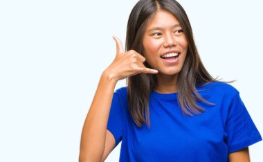 Genç Asyalı kadın yapıyor gülümseyen izole arka plan üzerinde telefon hareketi ile el ve parmak telefonda konuşuyor gibi. Kavramları iletişim.