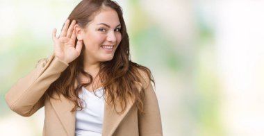 Artı boyutu genç kadın güzel üzerinde kış palto giyiyor arka plan bir işitme söylenti ya da dedikodu için dinleme kulak üzerinde el ile gülümseyen izole. Sağırlık kavramı.