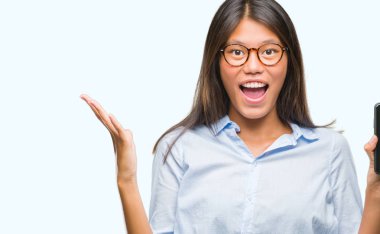 Genç Asyalı kadın Smartphone boş ekran üzerinde gösterilen büyük gülümseme ile çığlık zaferini kutluyor ve ellerini kaldırdı arka plan çok mutlu ve heyecanlı, kazanan ifade izole