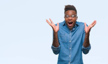 Afrikalı-Amerikalı genç deli kutluyor ve silah ile başarı için heyecanlı çığlık kaldırdı ve açık gözleri hayret izole arka plan üzerinde. Kazanan kavramı
