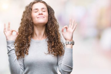 Güzel esmer kıvırcık saçlı Genç kız izole arka plan üzerinde bir kazak giyiyor rahatla ve gülümseyen gözlerle kapalı parmak jestle meditasyon yapıyor. Yoga kavramı.