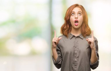 Genç güzel kadın izole arka plan üzerinden hayran ve yukarıya bakıp parmakları ile işaret şaşırttı ve silah kaldırdı.