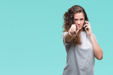 Genç esmer kız Smartphone'da konuşmayı kamera ve size parmak ile işaret arka plan izole, el işareti, pozitif ve kendinden emin bir jest ön