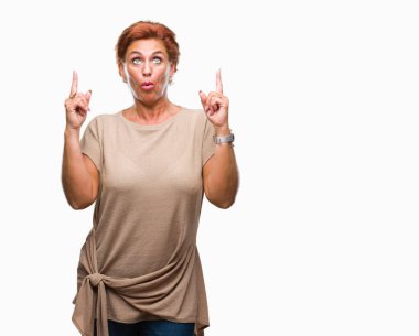 Atrractive üst düzey beyaz Kızıl saçlı kadın izole arka plan üzerinden hayran ve yukarıya bakıp parmakları ile işaret şaşırttı ve silah kaldırdı.