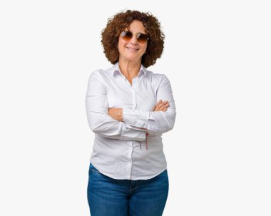 Üzerinde güneş gözlüğü takıyor güzel orta ager üst düzey iş kadını mutlu yüz ile gülümseyerek kameraya seyir silah geçti arka plan izole. Olumlu bir kişi.