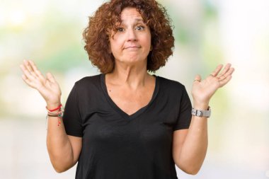 Güzel orta ager üst düzey kadın izole arka plan clueless ve şaşkın bir ifadeyle kollar ve eller kaldırdı. Şüphe kavramı.