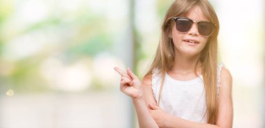 Genç Sarışın yürümeye başlayan çocuk el ve parmak ile tarafına işaret çok mutlu güneş gözlüğü takıyor