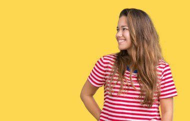 Uzak tarafına yüzünde, doğal ifade gülümseme ile seyir izole arka plan üzerinde tişört giyen genç güzel esmer kadın çizgili. Kendine güvenen gülüyor.