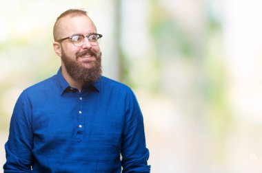 Görünümlü yan ve dik dik bakma uzağa düşünce gülümseyen izole arka plan üzerinde gözlüklü Genç beyaz hipster adam.