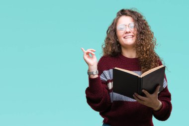 Genç esmer kız izole arka tarafına el ve parmak ile işaret çok mutlu üzerinde gözlük takan bir kitap okuma