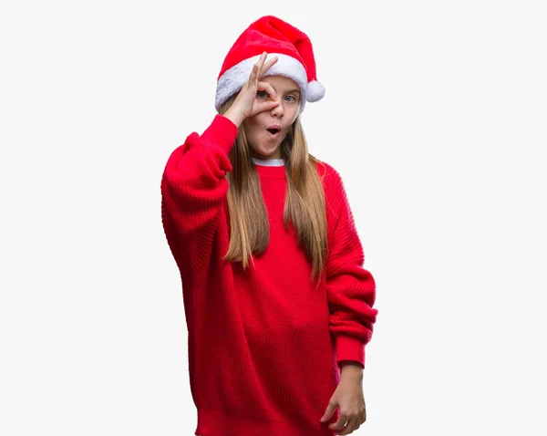 年轻美丽的女孩戴着圣诞帽在孤立的背景做确定的手势震惊与惊讶的脸 眼睛通过手指看 不相信的表达 — 图库照片