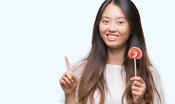 Young Asian Woman Eating Lollipop Candy Isolated Background Surprised Idea — Stock Photo, Image