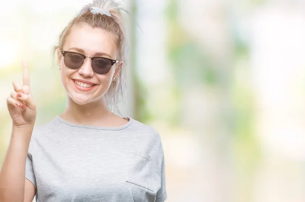 stock image Young blonde woman wearing sunglasses over isolated background pointing finger up with successful idea. Exited and happy. Number one.