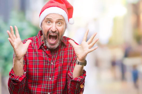 中年白髪年配の男性にクリスマスの帽子をかぶって狂気を祝う背景を分離した腕を上げると成功のためびっくりし 叫んで興奮して目を開きます 勝者の概念 — ストック写真