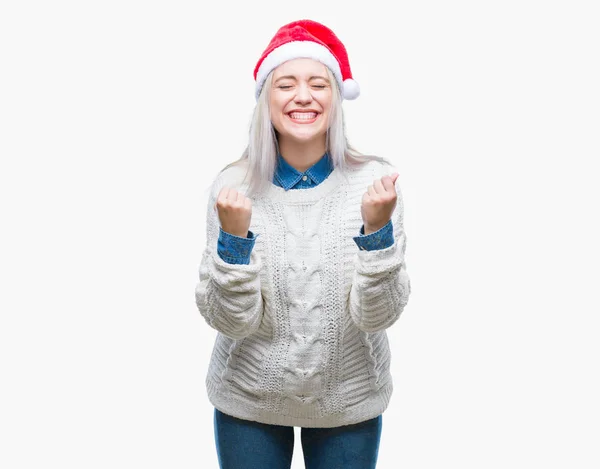 年轻的金发女子戴着圣诞礼帽 身披孤立无援的背景 非常高兴而兴奋地举起双臂 微笑着 尖叫着要成功 庆祝概念 — 图库照片