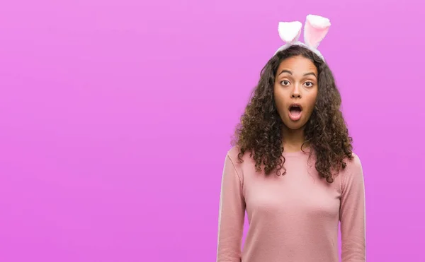 年轻的西班牙妇女戴复活节兔子耳朵吓得惊讶与惊喜的脸 害怕和兴奋的恐惧表情 — 图库照片
