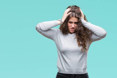 Güzel esmer kıvırcık saçlı Genç kız bir kazak giyiyor çünkü umutsuz ve stresli baş ağrısı acı izole arka plan üzerinde ağrı ve migren. Ellerini kafasına.