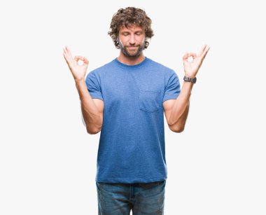 Yakışıklı İspanyol modeli adam izole arka plan üzerinde dinlenmek ve gülümseyen gözlerle parmak ile meditasyon jest yapıyor kapalı. Yoga kavramı.