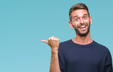 Seyir ve başparmak yanında yukarıyı mutlu yüz ile gülümseyen izole arka plan üzerinde kış kazak giyen genç yakışıklı adam.