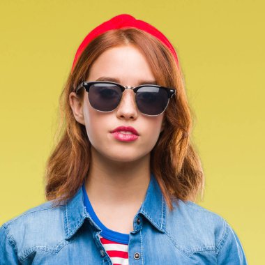 Genç güzel kadın yüzünden izole arka yüzünde ciddi bir ifade ile güneş gözlüğü takıyor. Basit ve doğal kameraya bakıyor.