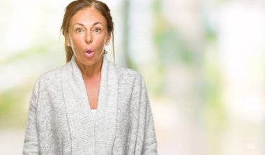 Güzel orta yaş yetişkin kadın giyiyor kış kazak korkuyor ve şok sürpriz ifade ile izole arka plan üzerinde korku ve yüz heyecanlı.