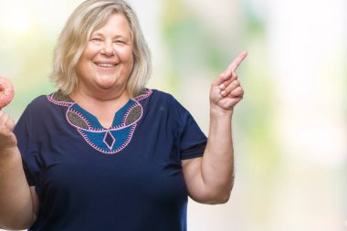 Üst düzey artı boyutu kafkas kadın izole arka tarafına el ve parmak ile işaret çok mutlu üzerinde şeker donut yemek