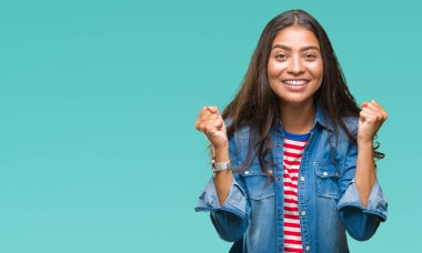 Genç güzel Arap kadın kutluyor izole arka plan üzerinde şaşırttı ve başarı için kaldırdı kollarını açarak hayret ve gözleri açık. Kazanan kavramı.