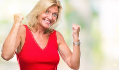 Gülümseyen ve başarı için çığlık orta yaş sarışın kadın izole arka plan çok mutlu ve heyecanlı kaldırdı, silah ile kazanan jest yapıyor. Kutlama kavramı.