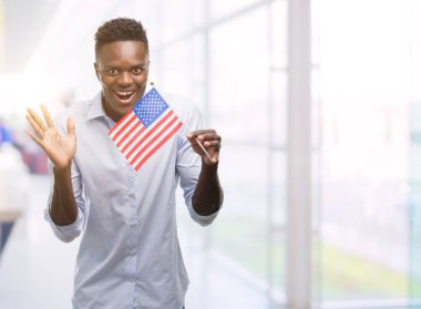 Çok mutlu ve heyecanlı, kazanan ifade büyük gülümseme ile çığlık zaferini kutluyor ABD bayrağı tutarak ve ellerini kaldırdı genç Afro-Amerikan adam
