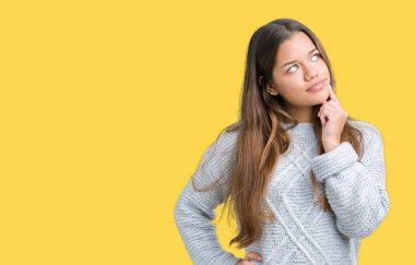 Çene düşünme hakkında soru, dalgın ifade üzerine el ile izole arka plan üzerinde kazak giyen genç güzel esmer kadın. Düşünceli yüzüyle gülümsüyor. Şüphe kavramı.