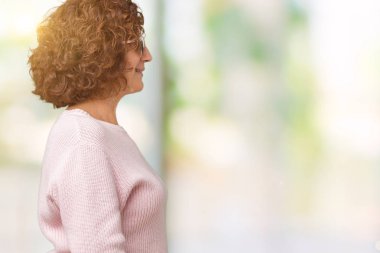 Pembe kazak ve güneş gözlüğü izole arka tarafına, seyir üzerinde giyen güzel orta ager üst düzey kadın dinlenmek doğal yüz emin gülümseme ile pozuyla profili.