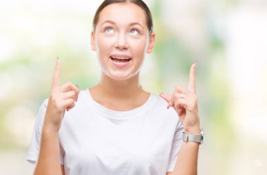 Genç güzel beyaz kadın üzerinden hayran ve yukarıya bakıyor ve parmakları ile işaret ve silah kaldırdı sürpriz izole arka plan.