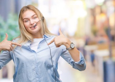 Yüzünde gülümseme ile kendinden emin görünüyorsun, kendini gururlu ve mutlu parmakları ile işaret izole arka plan üzerinde çağrı merkezi kulaklık giyen genç beyaz iş kadın.
