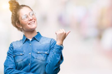 Seyir ve başparmak yanında yukarıyı mutlu yüz ile gülümseyen izole arka plan üzerinde gözlük güzel genç esmer kıvırcık saçlı kız.