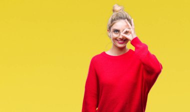 Gülümseyerek el parmakları ile mutlu yüz üzerinden seyir göz ile ok jest yapıyor izole arka plan üzerinde kırmızı kazak ve gözlük giyen genç güzel sarışın kadın.