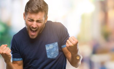 Soyutlanmış, mutlu ve heyecanlı genç bir adam kollarını kaldırmış, gülümseyen ve başarı için çığlık atan kazanan bir jest yapıyor. Kutlama konsepti.