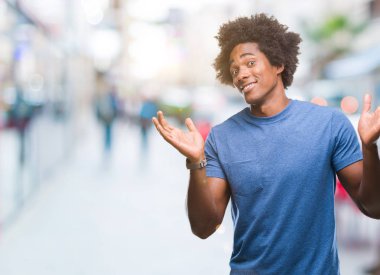 İzole arka plan clueless ve şaşkın bir ifadeyle kollar ve eller kaldırdı Afro Amerikan adam. Şüphe kavramı.