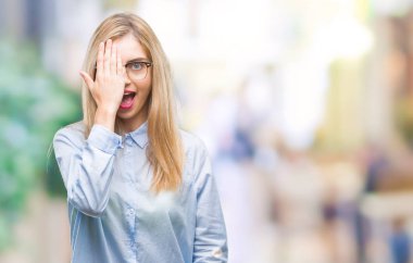 El yüz ve sürpriz duygu kendinden emin gülümseme ile tek gözüyle kapsayan izole arka plan üzerinde gözlük takan genç güzel sarışın iş kadını.