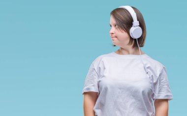 Down sendromlu uzak tarafına yüzünde, doğal ifade gülümseme ile seyir izole arka plan üzerinde kulaklık giyen genç yetişkin kadın. Kendine güvenen gülüyor.