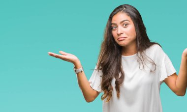 Genç güzel Arap kadın izole arka plan clueless ve şaşkın bir ifadeyle kollar ve eller kaldırdı. Şüphe kavramı.