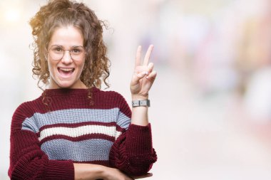 Güzel esmer kıvırcık saçlı Genç kız mutlu yüz zafer işareti yaparken kameraya göz kırpıyor ile gülümseyen izole arka plan üzerinde gözlük takıyorum. İki numaralı.