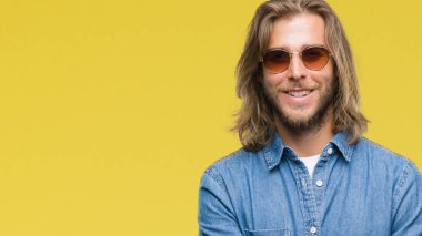 Mutlu yüz ile gülümseyerek kameraya seyir silah geçti arka plan üzerinde güneş gözlüğü takmış uzun saçlı yakışıklı delikanlı izole. Olumlu bir kişi.