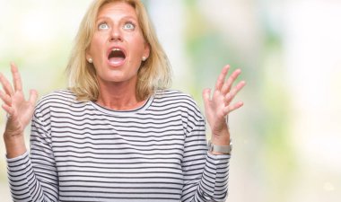 Orta yaş sarışın kadın izole arka plan çılgın ve kızgın bağırarak ve agresif ifade ve silah kaldırdı bağırıyor. Hayal kırıklığı kavramı.