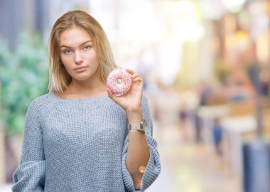 Acımak yüz ciddi düşünüyorum üstünde kendine güvenen bir ifade ile izole arka plan üzerinde tatlı çörek yiyen genç kafkas kadın