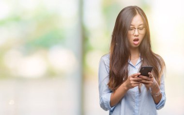 Genç Asyalı kadın manifatura Smartphone izole arka şok sürpriz yüzü, korkuyor ve korku ifadesi ile heyecanlı olan korkmuş üzerinde kullanma