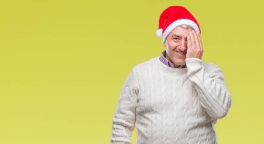 Üst düzey yakışıklı yüz ve sürpriz duygu kendinden emin gülümseme ile el ile bir göz kapsayan izole arka plan üzerinde Noel şapka.