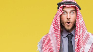 Genç yakışıklı Arap adam uzun saçlı izole arka plan korkuyor ve şok sürpriz ifade, korku ve heyecan yüz üzerinden keffiyeh giyiyor.