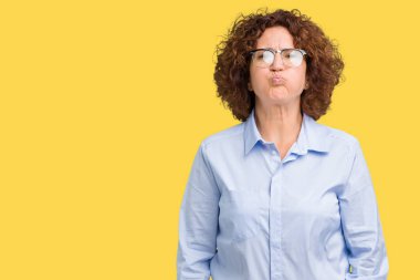 Komik surat ile yanakları şişirme izole arka plan üzerinde gözlük giyen güzel orta ager üst düzey businees kadın. Ağız ile hava, deli ifade şişirilmiş.