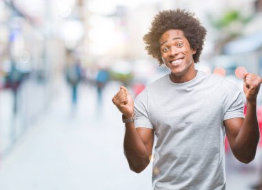 İzole arka plan kutlama üzerinde Afro Amerikalı adam şaşırttı ve başarı için kaldırdı kollarını açarak hayret ve gözleri açık. Kazanan kavramı.